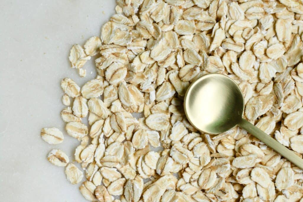 Oats on a table with golden spoon. Healthy fibre to tackle IBS.