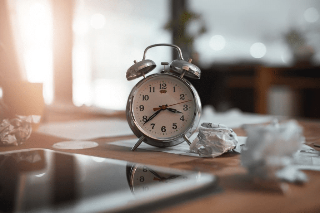 A back-lit by sunlight shot of clock on table with crumpled papers beside- signifying urgency of timing/ early detection.